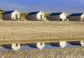 Cuatro cabañas de playa de lujo con techos azules en La Haya, perfectas para glamping junto al mar.