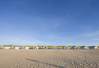 Rangée de cabanes de plage luxueuses sur le sable à La Haye, idéales pour le glamping et le camping.