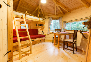 Indvendig billede af TreeLounge Boomhut Nedersaksen, hyggelig træhytte med soveplads og spisebord i skoven.