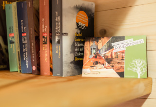 Een boekenplank met boeken en een TreeLounge-kaart die boomhutglamping in Cuxhaven promoot.