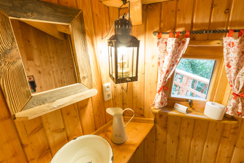 Rustikales Baumhaus-Interieur mit Waschbecken, Spiegel, Laterne und Fenster, Boomhut Nedersaksen Glamping.