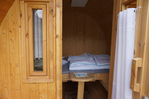 Ingang van een luxe houten slaapvat bij Mosel Islands glamping, met een gezellig bed binnenin.