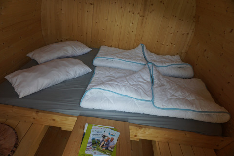 Interior view of a luxury sleeping barrel with double bed, pillows, and duvets at Mosel Islands glamping.