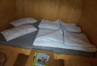 Innenaufnahme eines Luxus-Schlafbarrrels mit Doppelbett, Kissen und Bettdecken auf Mosel Islands Glamping.