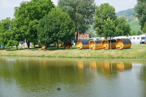 Glamping-Unterkunft mit luxuriösen Schlaf-Fässern an der Mosel, umgeben von Bäumen und Wohnwagen.