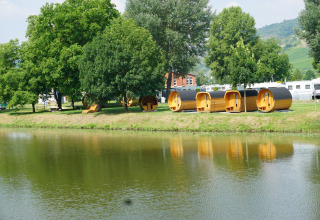 Glamping-Unterkunft mit luxuriösen Schlaf-Fässern an der Mosel, umgeben von Bäumen und Wohnwagen.