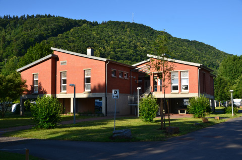 Glampingverblijf Mosel Islands met luxe rode slaapvaten aan de Moezel, omgeven door groene heuvels.