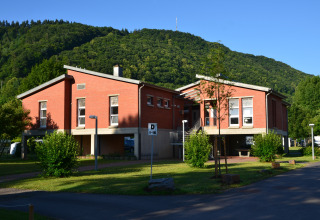 Glamping Mosel Islands avec logements en briques rouges, entourés de collines verdoyantes et de nature paisible.