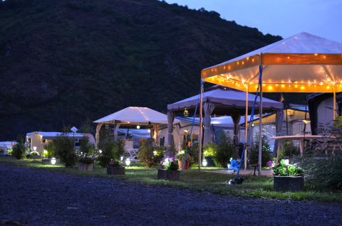 Glamping-Unterkünfte Mosel Islands an der Mosel mit beleuchteten Zelten und Blumen am Abend.