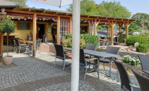Outdoor dining area with tables, chairs, plants, and pergola at Camping Tunisee - Stacaravans Baden-Württemberg.