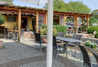 Buiten eetgedeelte met tafels, stoelen, planten en pergola bij Camping Tunisee - Stacaravans Baden-Württemberg.