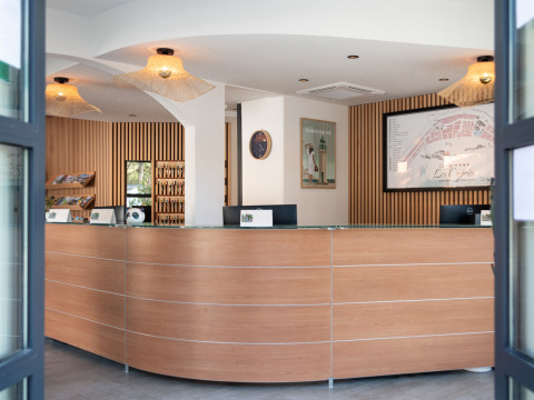Modern reception area of Camping Les Cyprès - Glampingtenten Vendée with wooden design and visitor brochures.