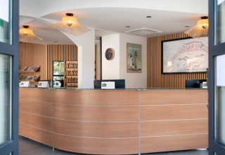 Modern reception area of Camping Les Cyprès - Glampingtenten Vendée with wooden design and visitor brochures.