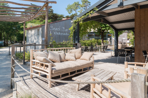 Espace lounge en plein air au Camping Les Cyprès - Glampingtenten Vendée, avec mobilier en bois et terrasse.