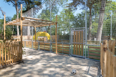 Spielplatz mit Ballspielfeld, Zaun und Basketballkorb bei Camping Les Cyprès - Glampingtenten Vendée.