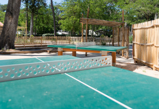 Tischtennisbereich im Freien bei Camping Les Cyprès - Glampingtenten Vendée mit Holzzäunen und Bäumen.
