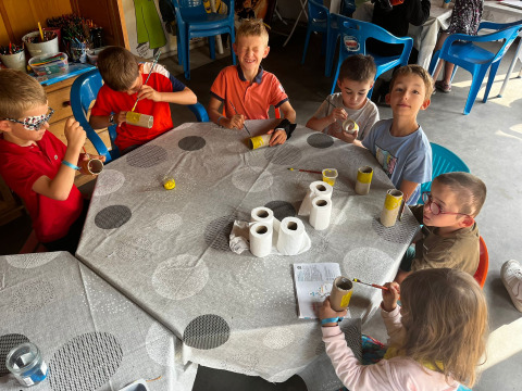 Children painting cardboard tubes at a creative workshop in Camping Les Cyprès - Glampingtenten Vendée.