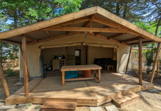 Hébergement glamping au Camping Les Cyprès en Vendée : tente spacieuse sur terrasse en bois entourée de nature.
