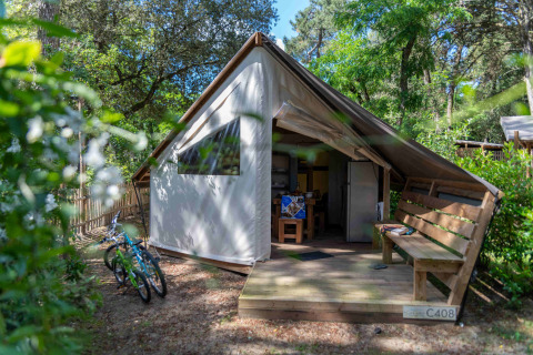 Tenda glamping al Camping Les Cyprès - Glampingtenten Vendée con veranda in legno e biciclette all’esterno.