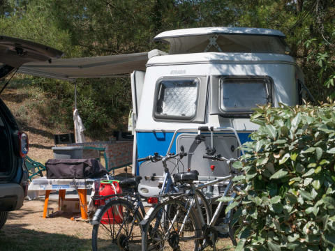 Kampeerplek met caravan, fietsen en zithoek buiten bij Camping Les Cyprès glampingtenten in Vendée, Frankrijk.