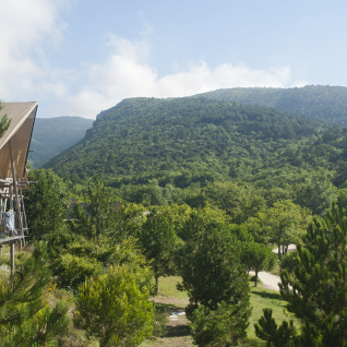 Alojamiento glamping en Village Huttopia Dieulefit con vistas a colinas verdes de Drôme-Provence.