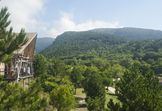 Alloggio glamping Village Huttopia Dieulefit con vista su colline e alberi verdi in Drôme-Provence.