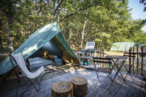 Comfortabele glampingtent met houten terras en tuinmeubels bij Village Huttopia Dieulefit in Drôme-Provence.