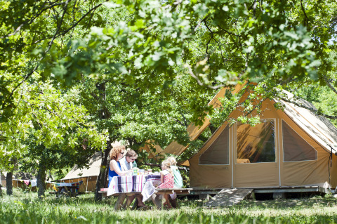 Famiglia mangia all'aperto vicino a una tenda glamping a Village Huttopia Dieulefit, Drôme-Provence.