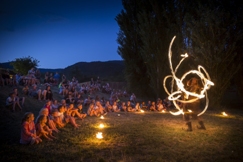 Spectacle de feu en soirée devant familles et enfants au Village Huttopia Dieulefit, Glamping Drôme-Provence.