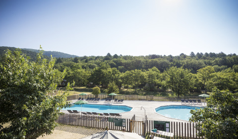 Vista di due piscine con lettini e alberi al Village Huttopia Dieulefit – Glamping Drôme-Provence.