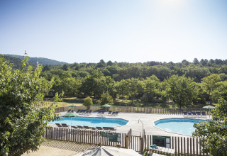 Uitzicht op twee zwembaden met ligstoelen en bomen bij Village Huttopia Dieulefit – Glamping Drôme-Provence.