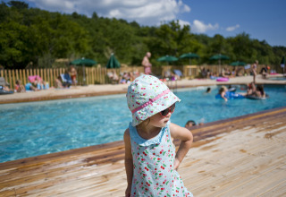 A child stands by the pool at Village Huttopia Dieulefit – Glamping Drôme-Provence on a sunny day.