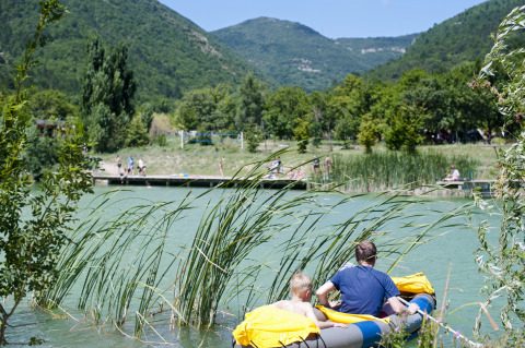 Due persone in un gommone su un lago circondato da colline e natura presso Village Huttopia Dieulefit.