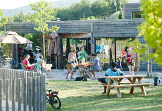 Mensen genieten van het buitenleven bij Village Huttopia Dieulefit – Glamping Drôme-Provence in een groene omgeving.