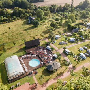 Vista aérea de Huttopia Calvados-Normandie, glamping con piscina, tiendas, caravanas y mucho verde alrededor.