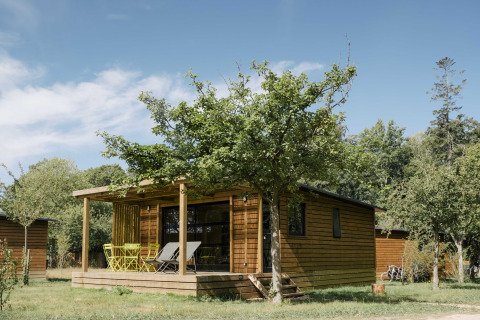 Hébergement glamping à Huttopia Calvados-Normandie, cabane entourée d’arbres pour un séjour de luxe en Normandie.