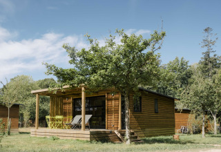 Glamping-Unterkunft bei Huttopia Calvados-Normandie mit Holzchalet, umgeben von grüner Natur in der Normandie.