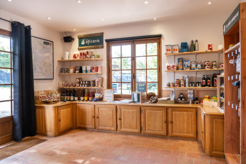 Tienda en Huttopia Calvados-Normandie con estantes de comestibles y productos locales en un ambiente acogedor.