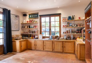 Butik i Huttopia Calvados-Normandie camping med lokale produkter og dagligvarer på hylder og træskabe.