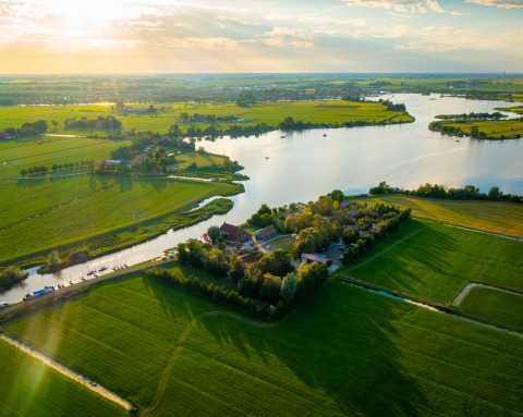 Luchtfoto van Pean Buiten - Natuurhuisjes Friesland glamping, omringd door velden en waterwegen.