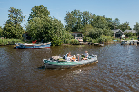 Gezin op een bootje voor Pean Buiten glamping, Natuurhuisjes Friesland aan het water in Nederland.