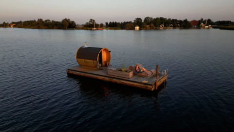 Floating glamping platform with sauna and lounge chairs on a lake at Pean Buiten, Friesland, Netherlands.