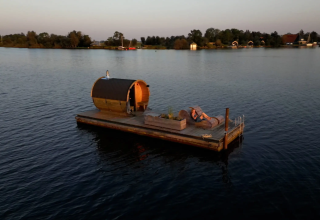 Flydende glamping-platform med sauna og liggestole på sø, omgivet af natur, Pean Buiten, Friesland.