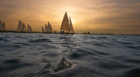 Zeilboten op het water bij Pean Buiten - Natuurhuisjes Friesland tijdens een sfeervolle zonsondergang.