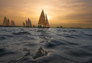 Sailboats on a lake at sunset near Pean Buiten - Natuurhuisjes Friesland, a peaceful glamping getaway.