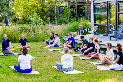 Groepsmeditatie buiten op het gras bij Pean Buiten - Natuurhuisjes Friesland glamping accommodatie.