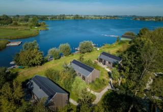 Vista aerea del glamping Pean Buiten con casette, pannelli solari e lago in Frisia, Paesi Bassi.