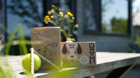 Regalos para perros como una pelota y bolsas ecológicas sobre una mesa en Pean Buiten - Natuurhuisjes Friesland.