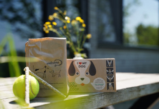 Regalos para perros como una pelota y bolsas ecológicas sobre una mesa en Pean Buiten - Natuurhuisjes Friesland.