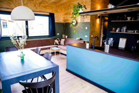 Modern glamping accommodation with open kitchen, dining table and sofa in Pean Buiten - Natuurhuisjes Friesland.
